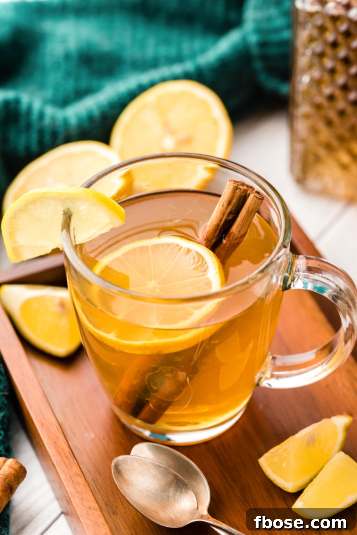 A clear mug filled with a hot toddy with a lemon slice and cinnamon stick, looking warm and inviting.