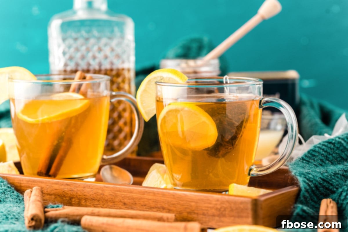 Two mugs on a wooden tray, filled with a hot toddy, ready to be enjoyed.