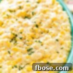 Close up photo of a teal serving dish filled with cheesy corn.