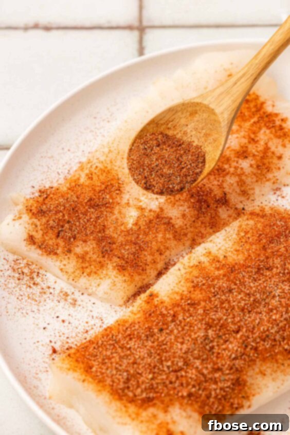 Seasoning being sprinkled on cod.