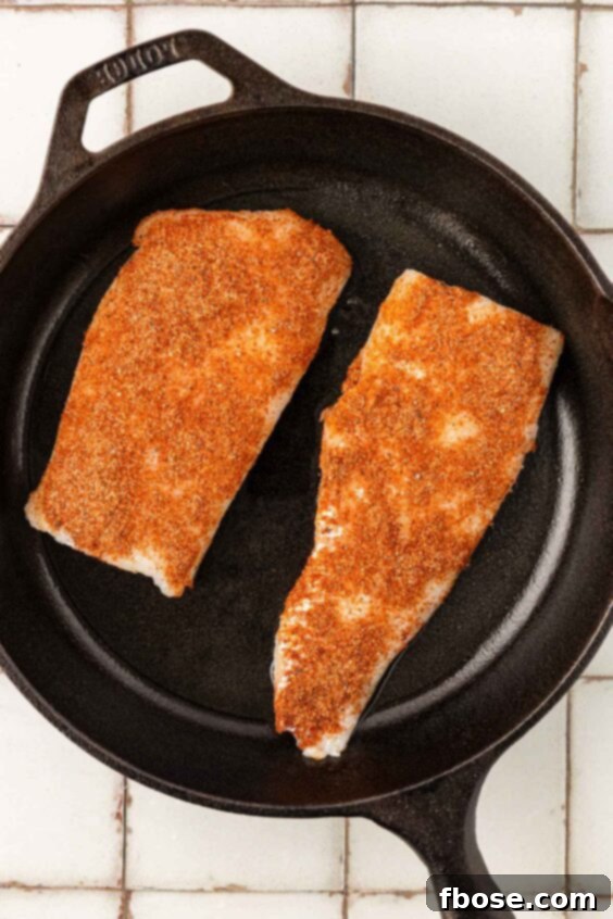 Seasoned cod in a cast iron skillet.