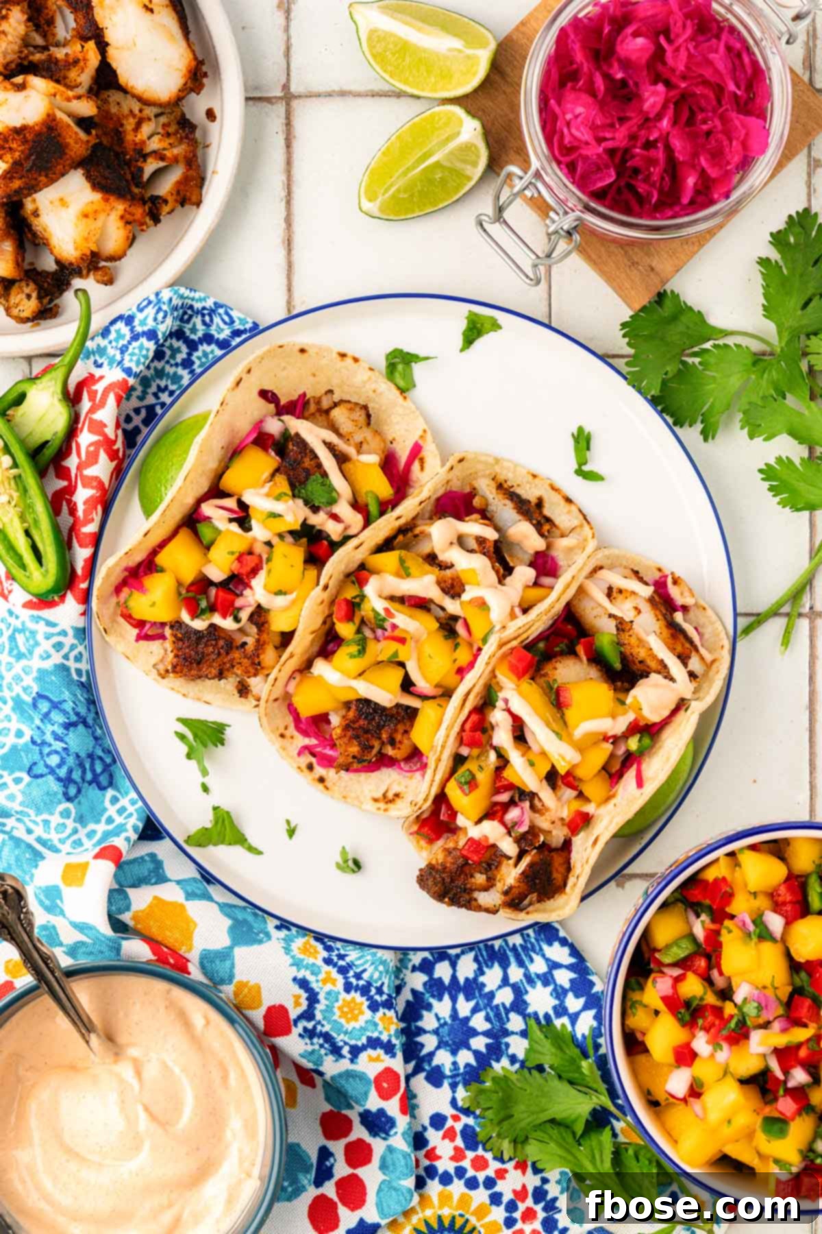 Overhead photo of three fish tacos beautifully arranged on a white plate, ready to be enjoyed.