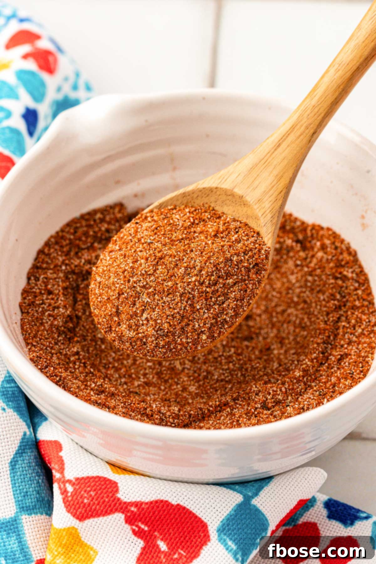 A bowl filled with fish taco seasoning, accompanied by a wooden spoon, ready for seasoning.