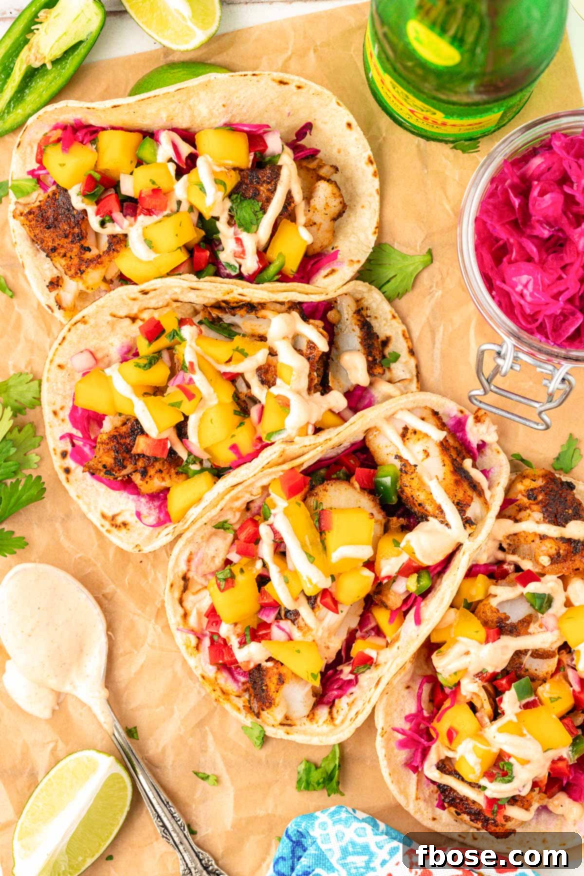 An inviting overhead photo of five colorful cod fish tacos artfully arranged on a clean table.