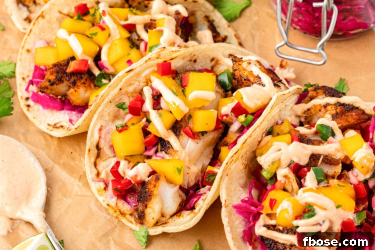 A close-up view of two beautifully assembled blackened cod tacos resting on a piece of parchment paper.
