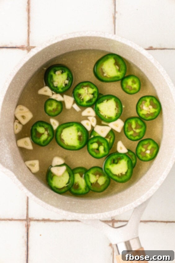 Jalapenos, garlic, vinegar, and more in a saucepan.