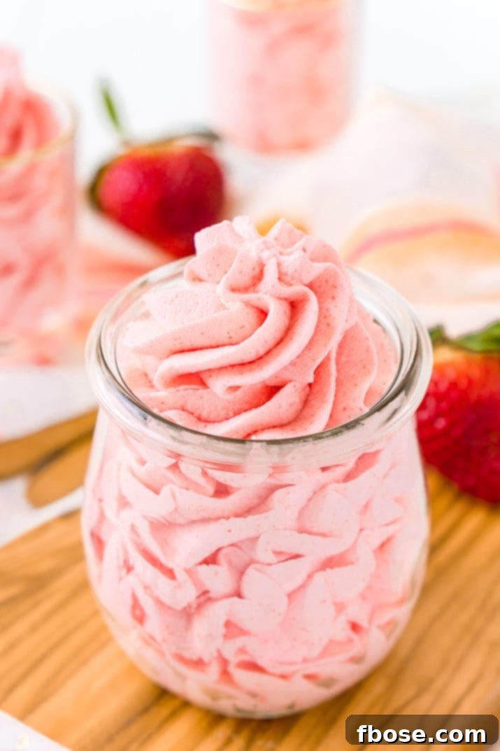 Fluffy, vibrant pink strawberry frosting piped beautifully on a cupcake, ready to be enjoyed.