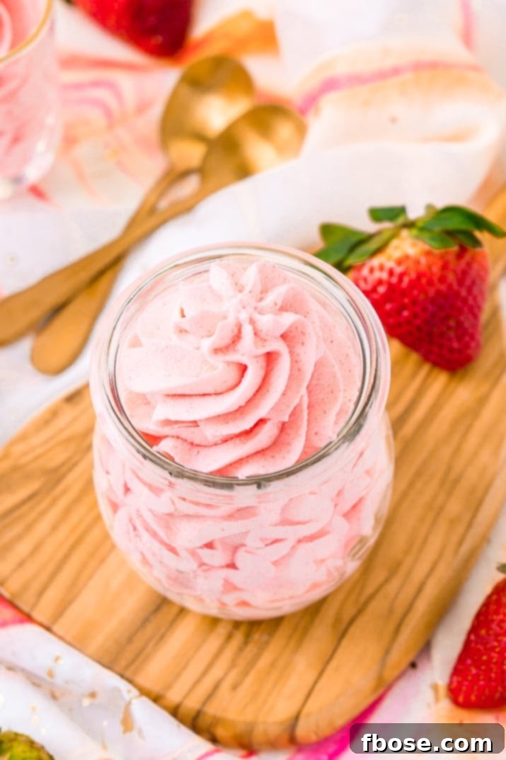 Close-up of a luscious bowl of homemade strawberry frosting, showcasing its smooth texture and vibrant pink color, perfect for any dessert.