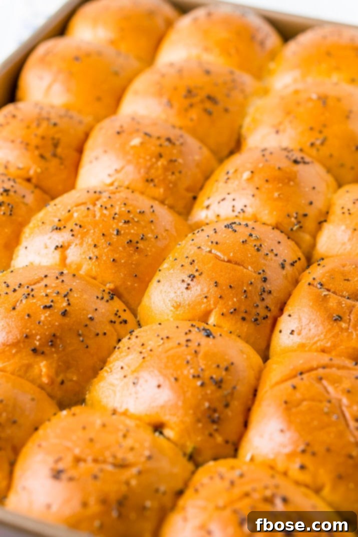 Close-up of golden brown Ham and Cheese Sliders on Hawaiian Rolls with melted cheese, ready to serve.