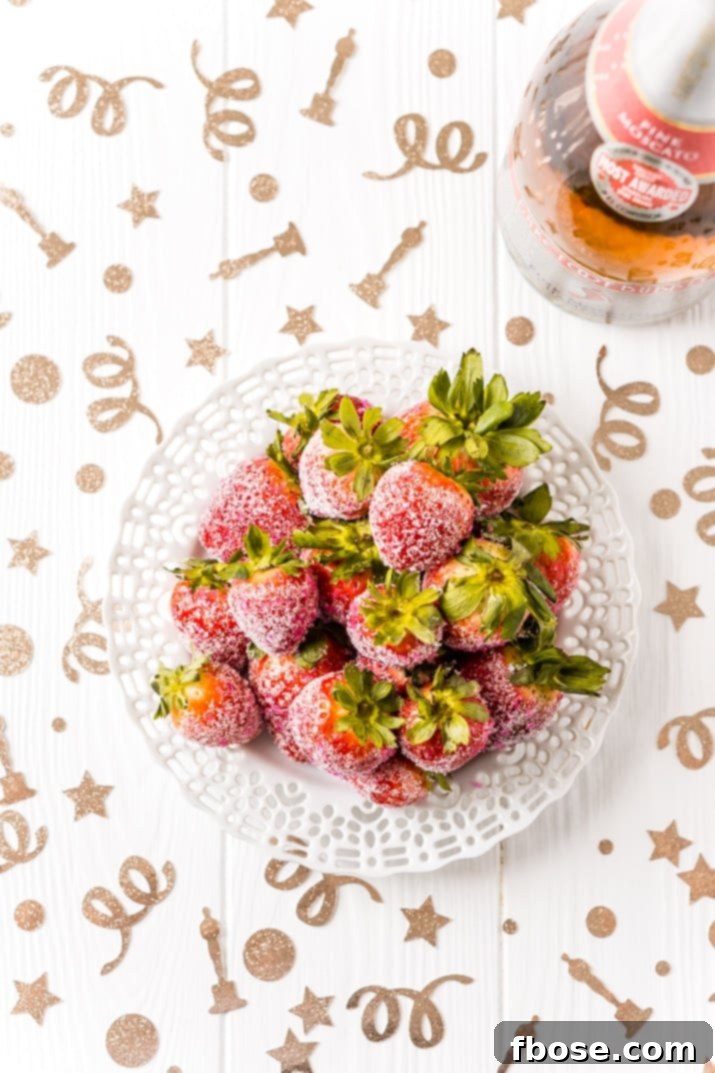 Close-up of fresh strawberries soaking in pink Moscato champagne, ready to be coated in sugar for a party dessert.