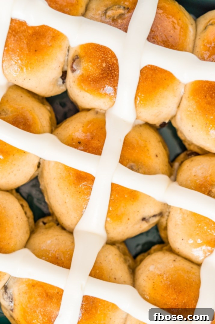 An overhead shot of a pan filled with beautifully iced hot cross buns, ready to be served.