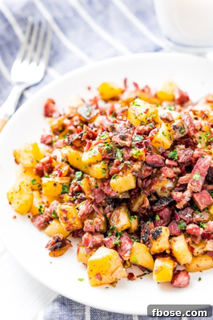 Ultimate Skillet Corned Beef Hash 5 Corned Beef Hash on white plate with fork and blue striped napkin