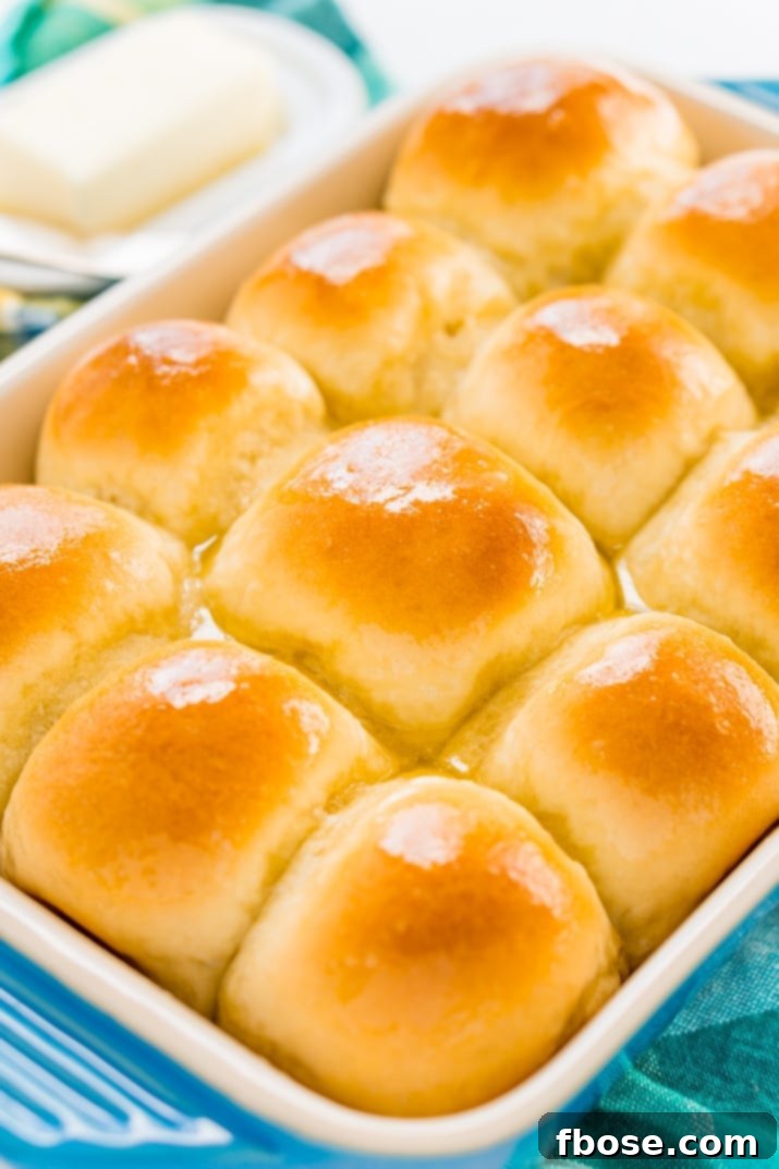 Close-up shot of warm, buttery yeast rolls arranged neatly in a baking pan, fresh from the oven.