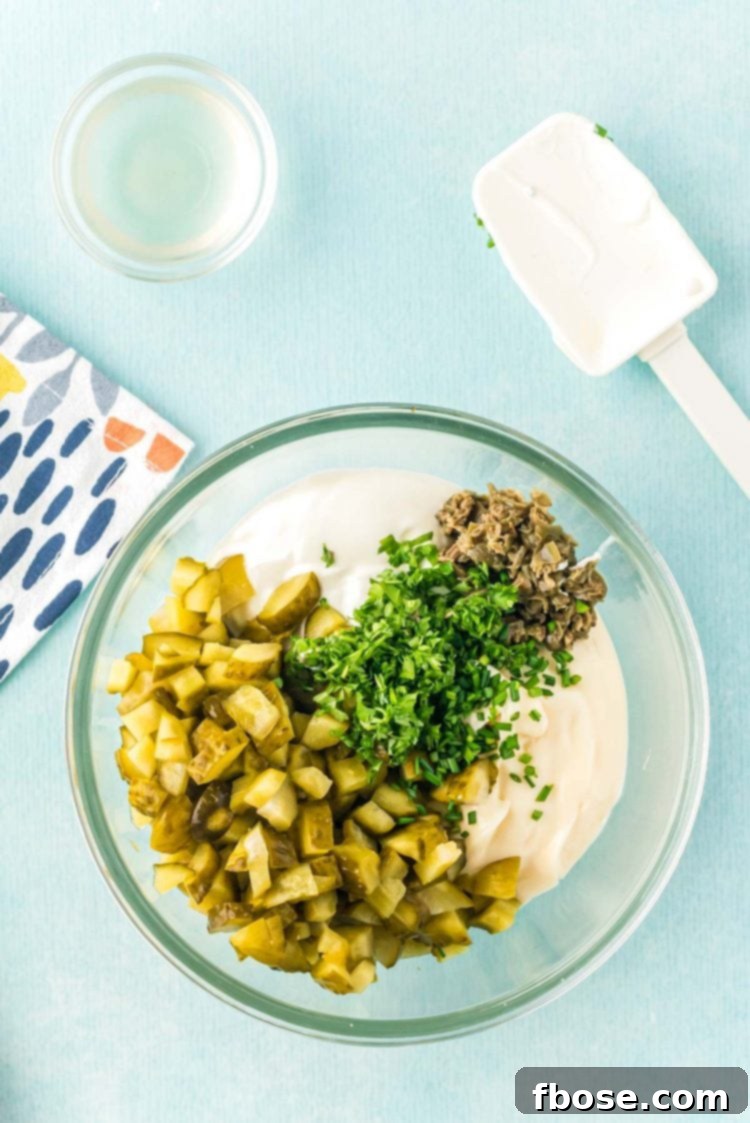 A large glass bowl filled with freshly mixed homemade tartar sauce, glistening under the light, signaling readiness to be served or chilled.