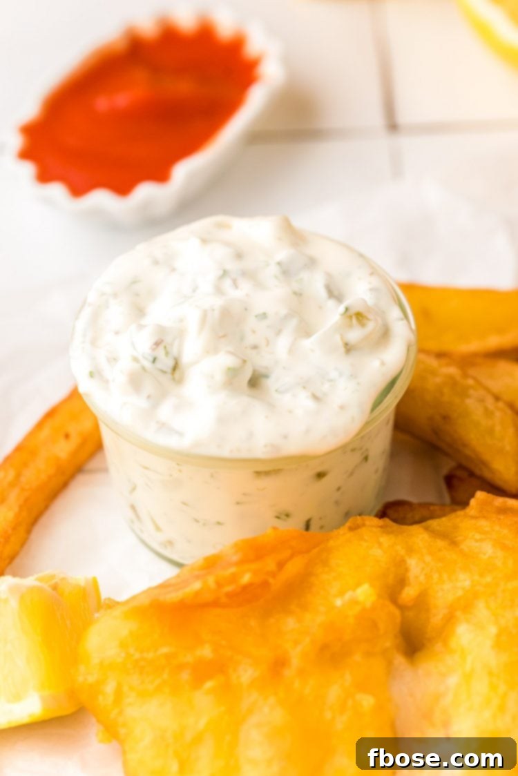 A perfect seafood meal: a jar of homemade tartar sauce, a plate of golden fried fish, and crispy chips, all ready to be enjoyed.