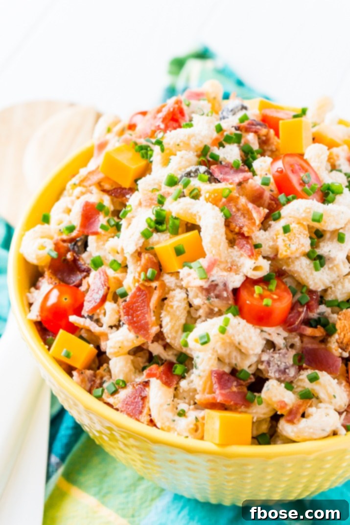 A vibrant bowl of Chicken Bacon Ranch Pasta Salad, loaded with pasta, chicken, bacon, cheese, and olives, glistening with creamy ranch dressing, perfect for summer barbecues.
