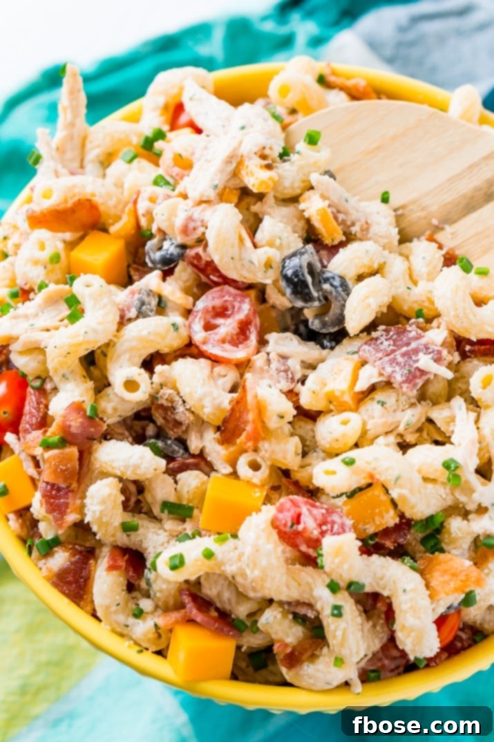 A vibrant close-up of the Chicken Bacon Ranch Pasta Salad in a bowl, showing the colorful mix of ingredients and creamy dressing, inviting you to take a bite.