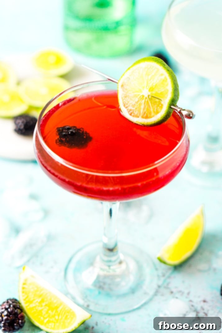 Blackberry gimlet cocktail garnished with a fresh lime slice and plump blackberries, showcasing its vibrant color and inviting appeal.