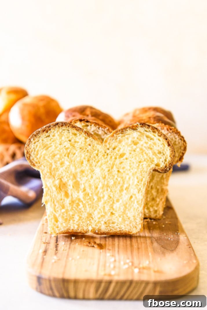 Perfectly sliced brioche bread laid out on a wooden cutting board, showcasing its fine, golden crumb and inviting texture, ready for serving.