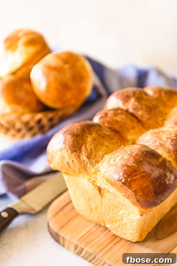 A perfectly baked, golden-brown whole loaf of brioche resting on a wooden cutting board, its crust glistening, promising a delightful interior.