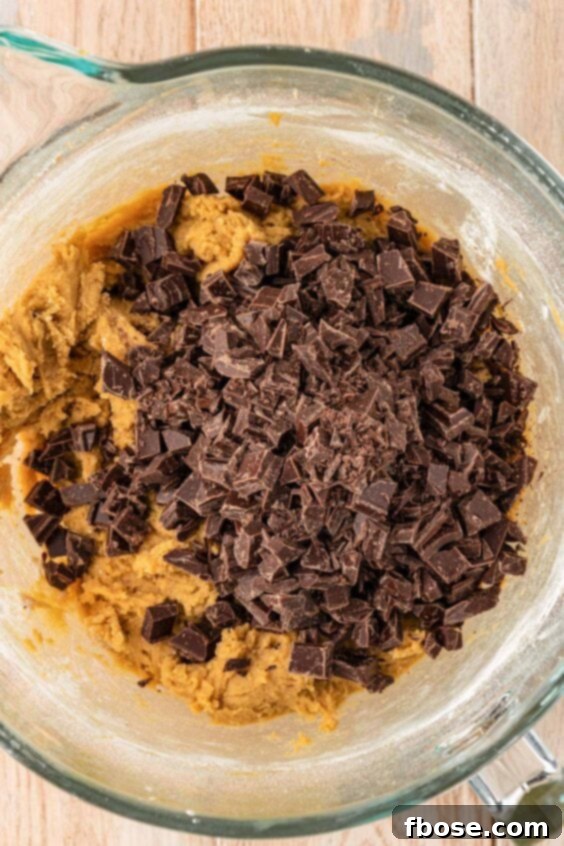 The Definitive Chocolate Chip Cookie 14 Chopped Chocolate being added to cookie dough.