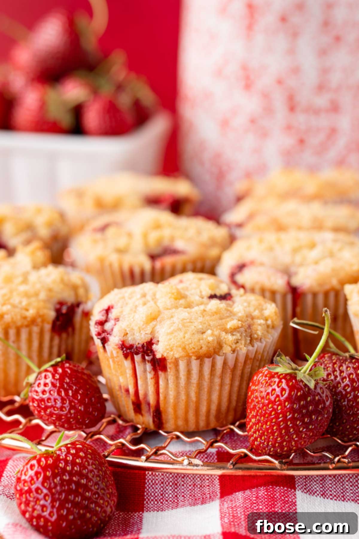 Delicious Strawberry Muffins 7 Strawberry muffins on a copper wire rack on a gingham napkin.
