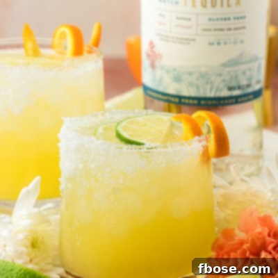 Two skinny margaritas on a brown table.