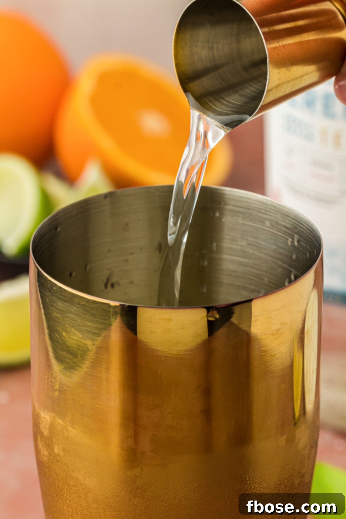 Tequila being added to a cocktail shaker.