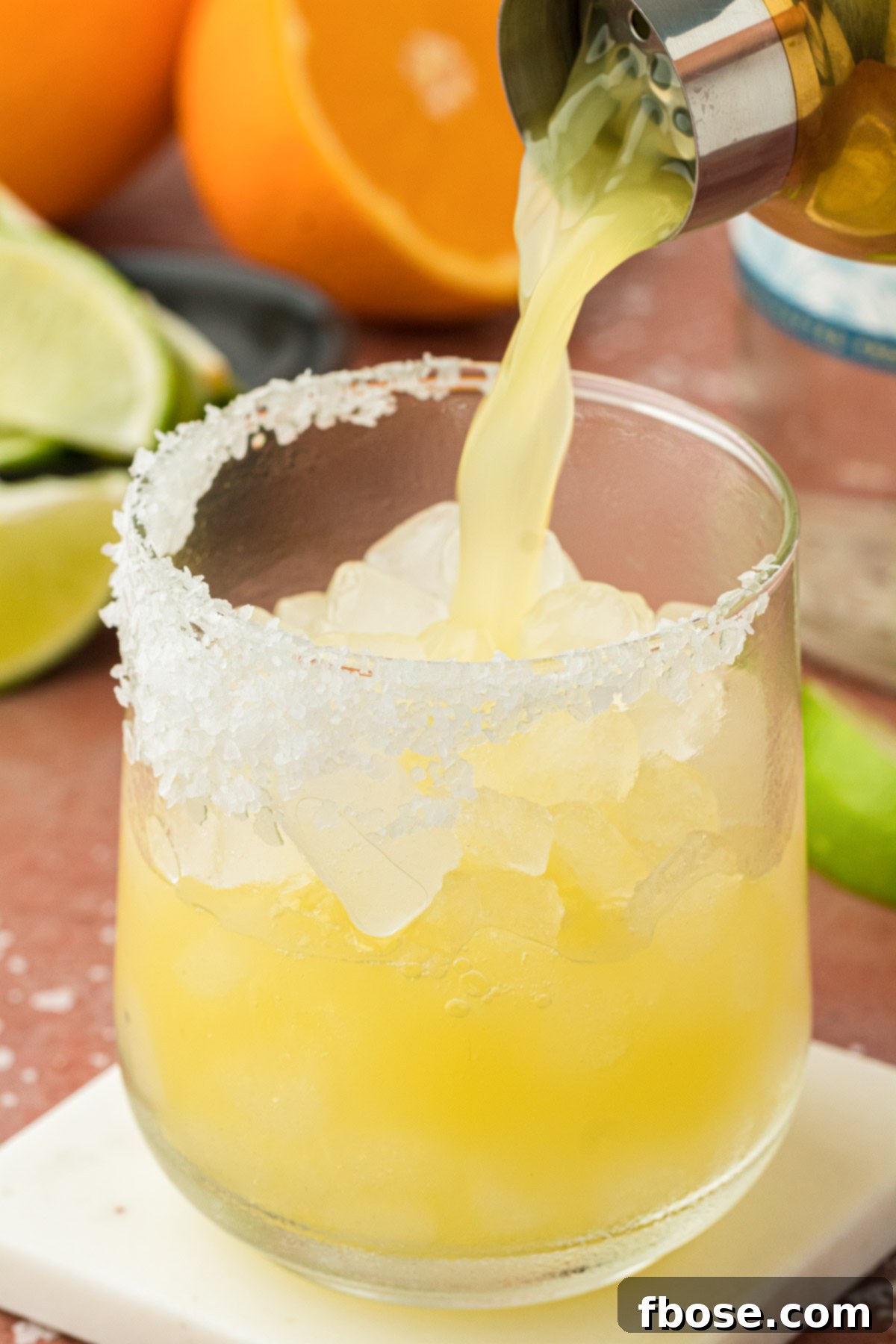 A skinny margarita being strained into a glass from a cocktail shaker.