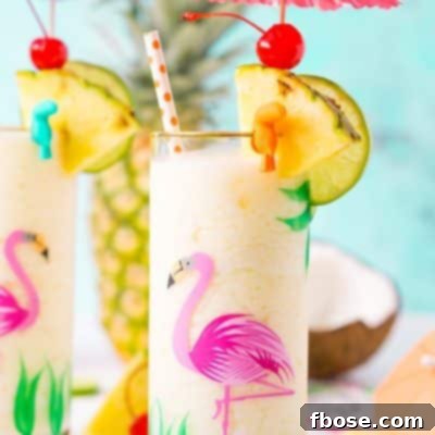 Glass with a flamingo painted on it with a pina colada in it topped with a drink umbrella and pineapple wedge.