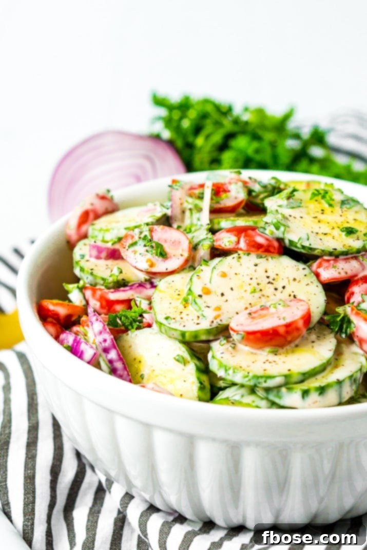 Overhead view of a prepared Tomato Cucumber Salad in a clear glass bowl, artfully arranged and ready to be served, highlighting the fresh ingredients and vibrant colors.