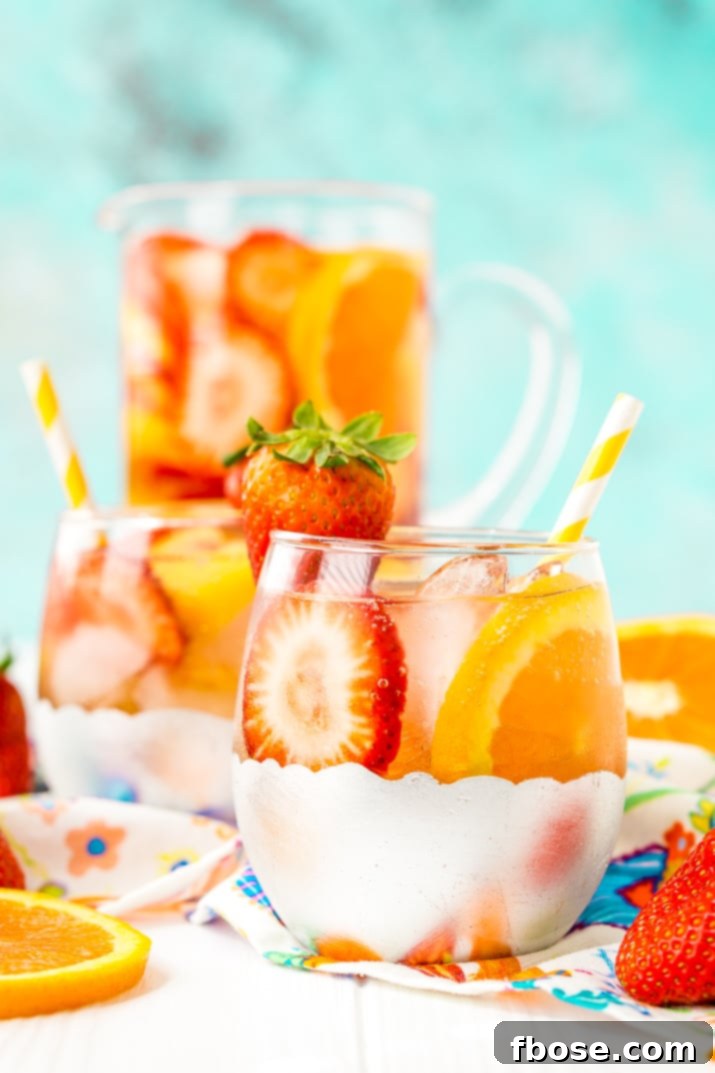 A refreshing pitcher of White Wine Sangria, featuring strawberries, oranges, peaches, simple syrup, apricot brandy, and club soda, ready to be enjoyed as a summer wine cocktail.