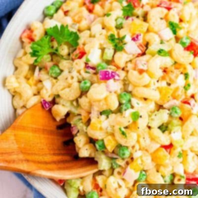 A wooden serving spoon scooping out of a macaroni salad.