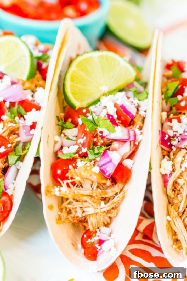 Savory Pulled Chicken Tacos 7 A close-up shot of a single shredded chicken taco with fresh avocado and cilantro