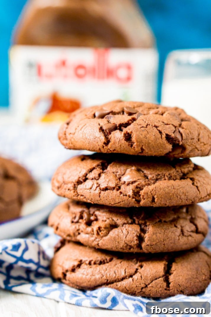 Gooey Nutella Stuffed Cookies 3 Close up photo of a stack of Nutella stuffed chocolate cookies on a blue and white napkin.