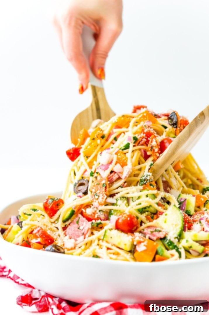 A close-up of colorful Spaghetti Salad with chunks of pepperoni, salami, and various vegetables coated in a light dressing.