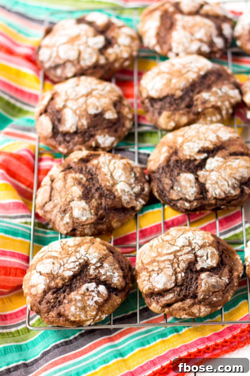 Stack of four chocolate Cool Whip Cookies with powdered sugar, ready to be enjoyed.