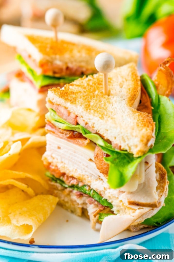 This Club Sandwich Recipe features layers of hickory smoked turkey breast, Swiss cheese, thick-cut bacon, crisp lettuce, ripe tomato, and creamy mayonnaise, all nestled between slices of perfectly toasted bread.