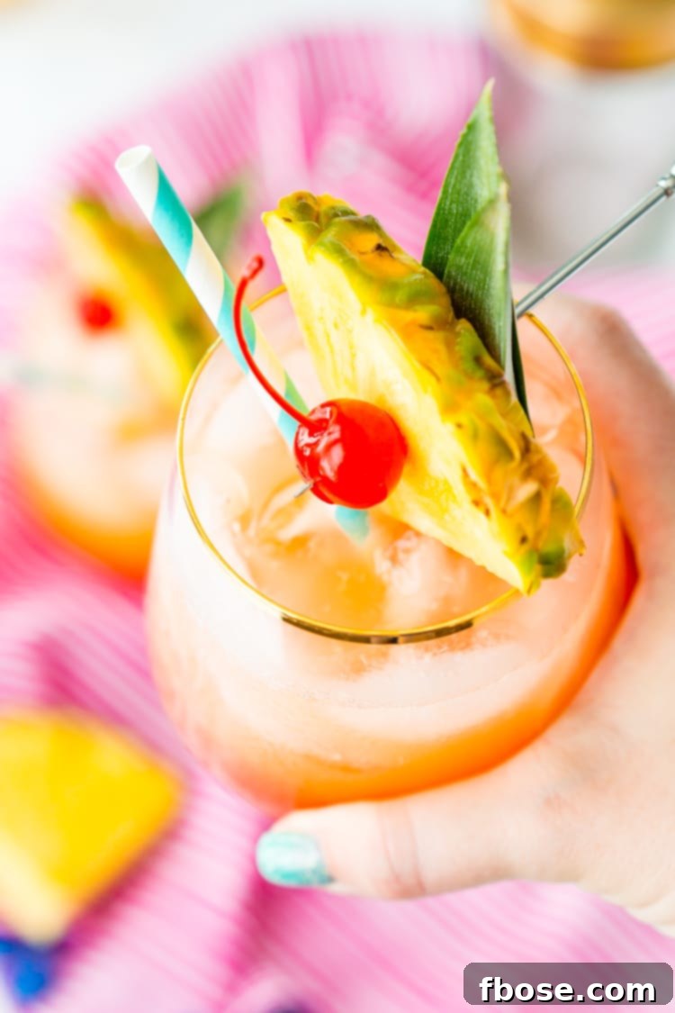 Close-up of a Mai Tai cocktail showing its beautiful layered colors of orange and pink, ready to be enjoyed.
