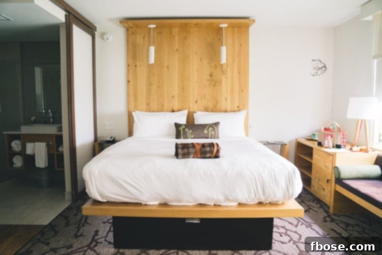 Unlocking Burlington: Essential Experiences in Vermont 4 A beautifully appointed hotel room at Hotel Vermont, featuring a crisp white bed, modern wooden furniture, and warm lighting, promising comfort and style.