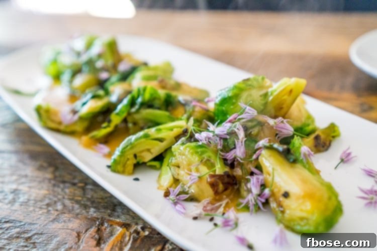 Unlocking Burlington: Essential Experiences in Vermont 7 Perfectly roasted Brussels Sprouts served on a platter with a savory sauce, a signature dish from Revolution Kitchen in Burlington.