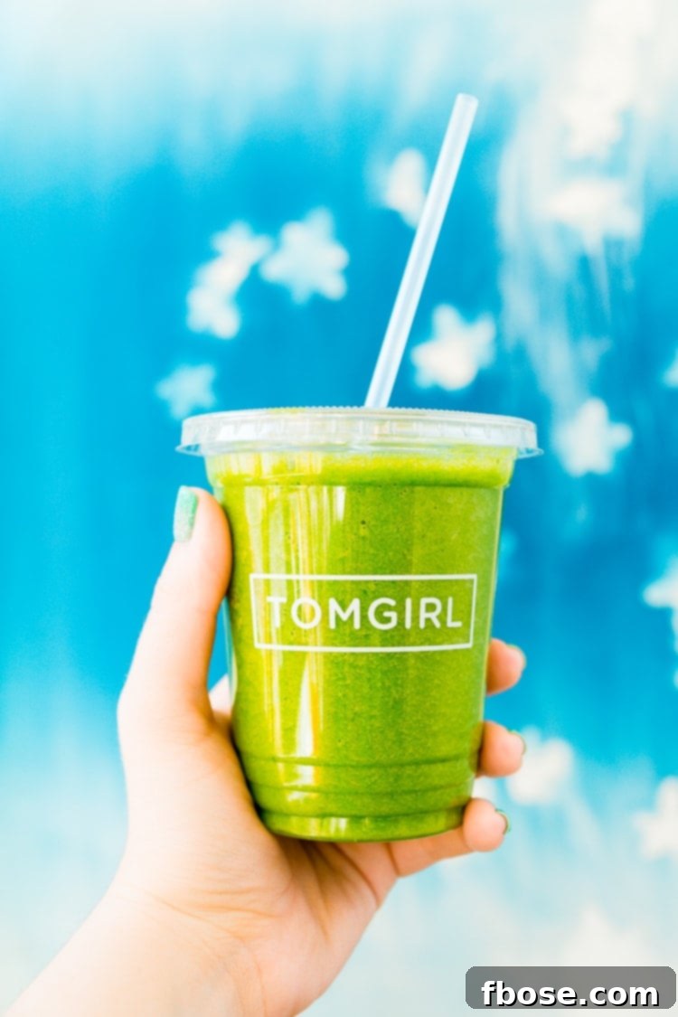 Unlocking Burlington: Essential Experiences in Vermont 8 A hand holding a stylish to-go cup from TOMGIRL Juice Co., showcasing a healthy and refreshing option in Burlington.