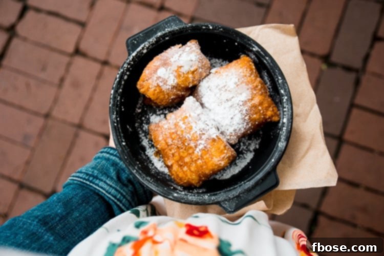 Unlocking Burlington: Essential Experiences in Vermont 10 Golden brown beignets generously dusted with powdered sugar, served fresh in a pan, a specialty of Leunig's Petit Bijou.