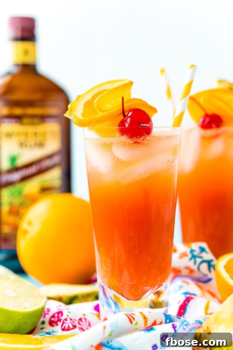 Planter's Punch: A Caribbean Classic 2 Two glasses filled with Planter's Punch, garnished with orange slices and cherries, with a bottle of rum blurred in the background, evoking a tropical, party-ready atmosphere.