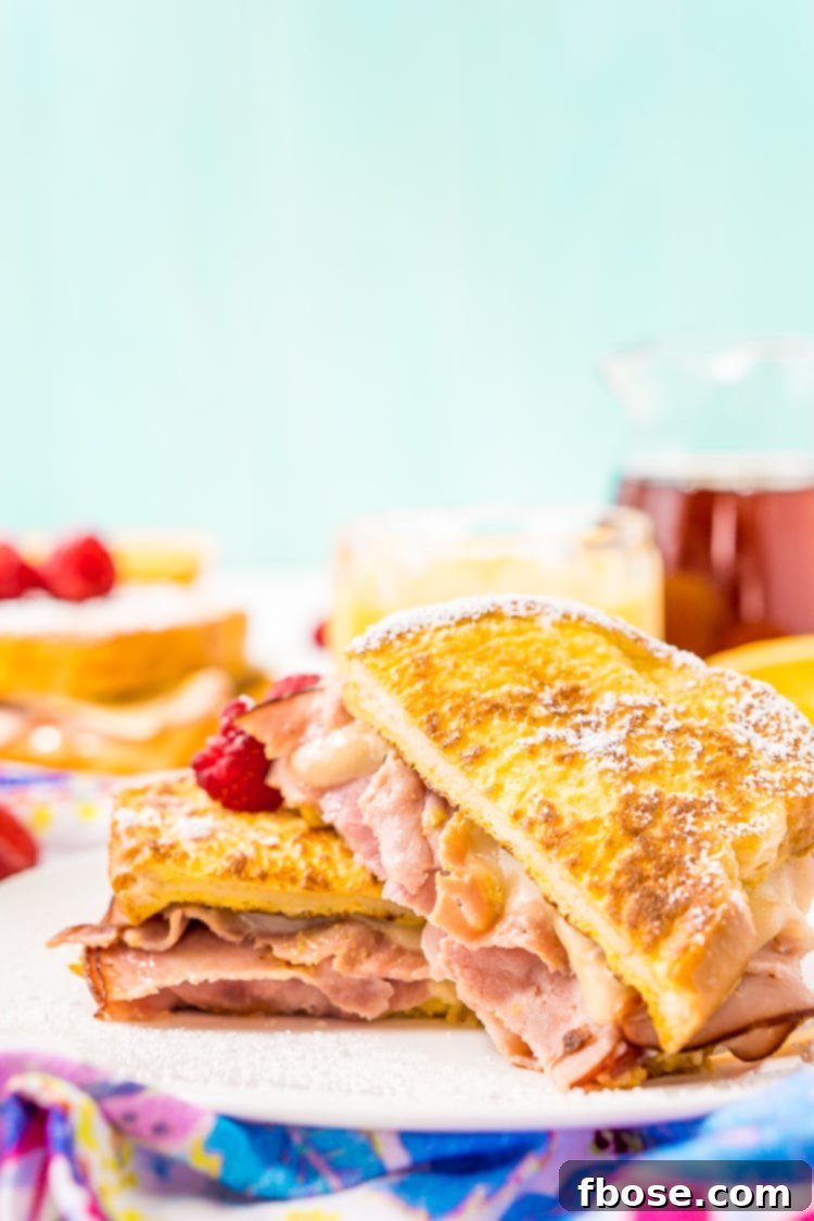 A beautifully prepared Monte Cristo Sandwich, showcasing its golden French toast exterior with a glimpse of the ham and cheese filling, ready to be drizzled with syrup and sprinkled with powdered sugar.