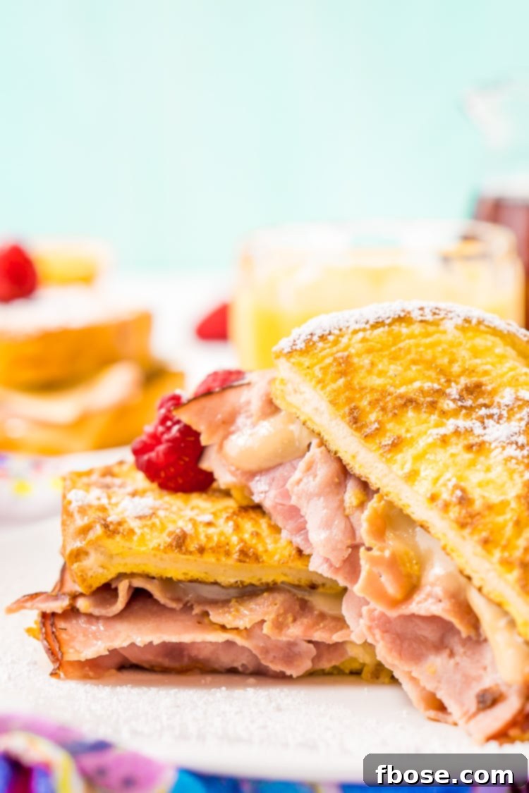 A close-up shot of a Monte Cristo Sandwich being prepared, showing the delicate slices of ham and melting Swiss cheese tucked between thick slices of bread, ready for the egg wash.