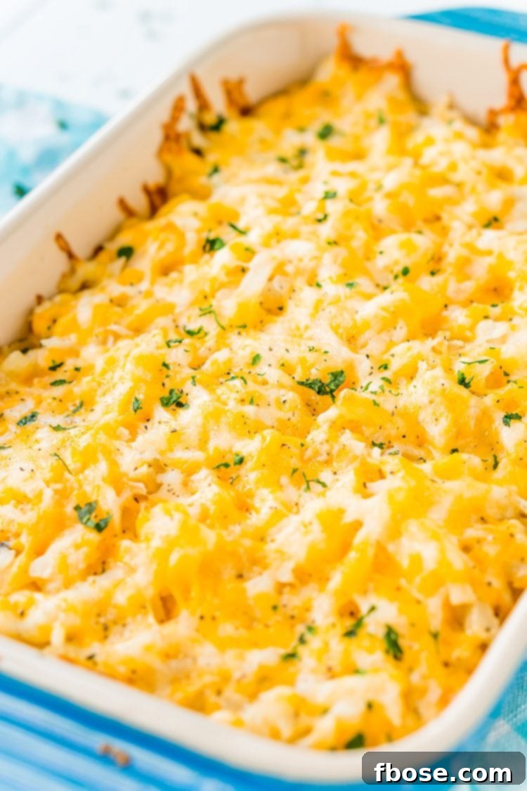 Close-up of golden brown, cheesy Hashbrown Casserole in a blue baking dish, showcasing its irresistible texture.
