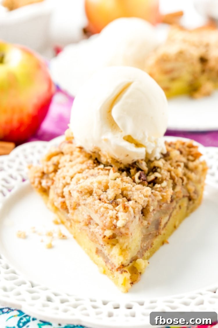 A large slice of Impossible French Apple Pie, showcasing the layers of apple, self-forming crust, and crumbly topping.