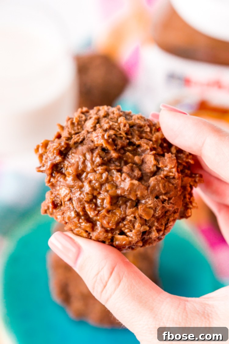 A stack of perfectly set Nutella No Bake Cookies on wax paper, showcasing their appealing round shapes and rich brown color.
