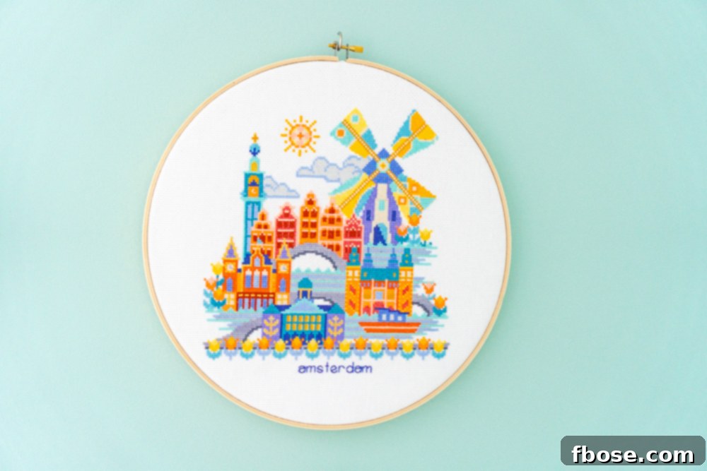 Charming Amsterdam cross-stitch hoop art, featuring canals and classic Dutch architecture, bringing a European flair to the nursery decor.